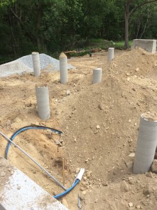 Fill going in around the foundation and concrete piers. Water line to the geothermal well in the foreground